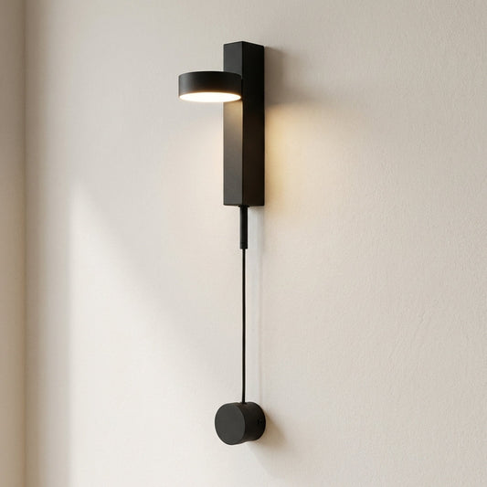 Modern black wall lamp with a cable extension on a light beige wall.