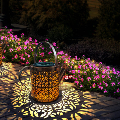 Decorative lantern casting shadows on a garden path with pink flowers and string lights.
